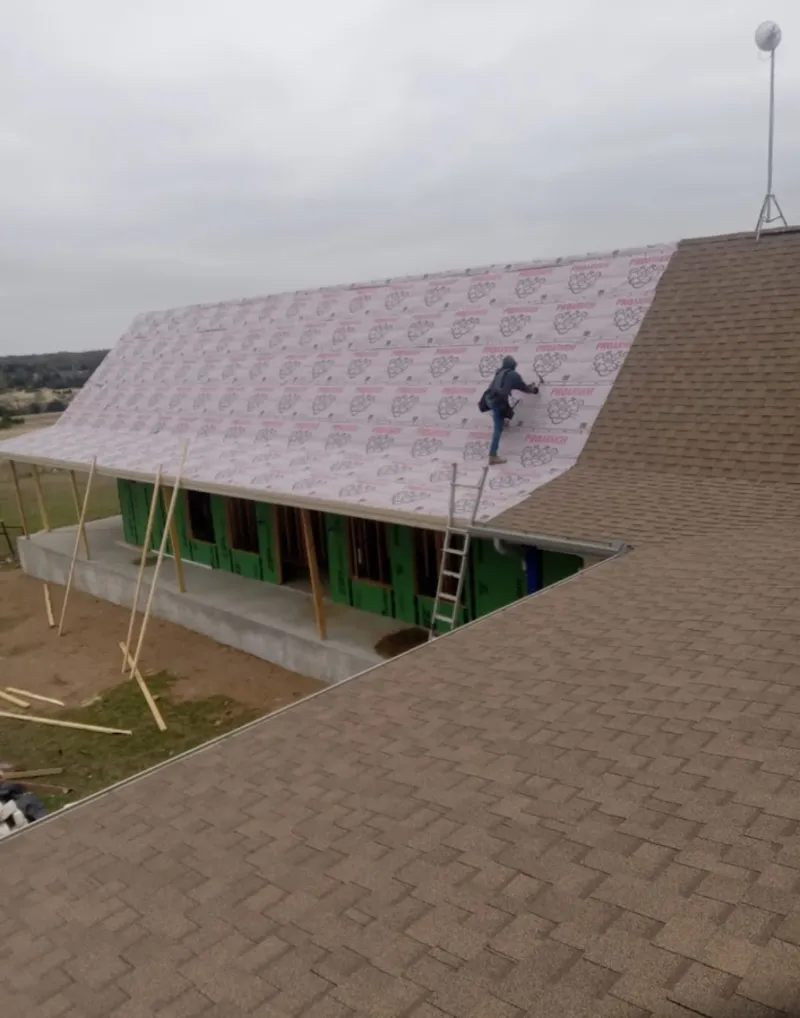 Worker preparing underlayment for a metal roof installation in North Hanover